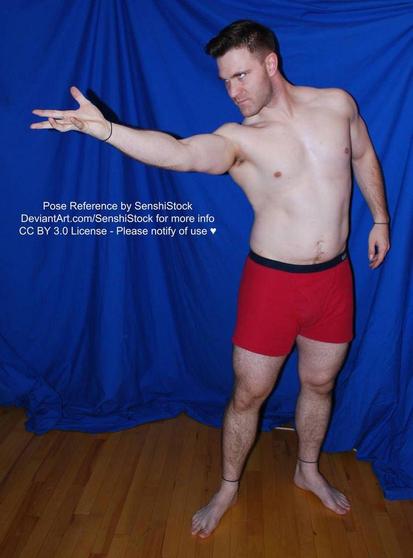 A white man standing and extending an arm, hand upward, like he is casting a spell.