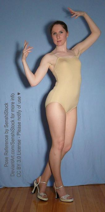 A white woman standing, both arms raised, one higher than the other.