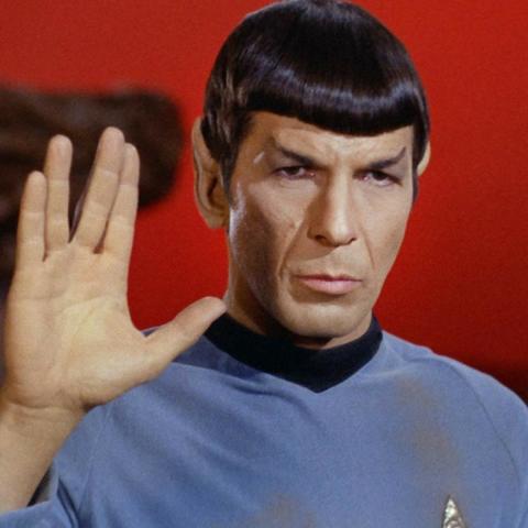 Spock in blauer Uniform mit dem bekannten Handzeichen und emotionslosem Ausdruck