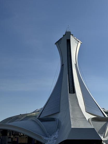 The Olympic Stadium in Montréal. The sky is blue. 

The tower is creating a slanted ramp towards the sky. 
- - -
Le stade olympique de Montréal. Le ciel est bleu.

La tour crée une rampe inclinée vers le ciel.