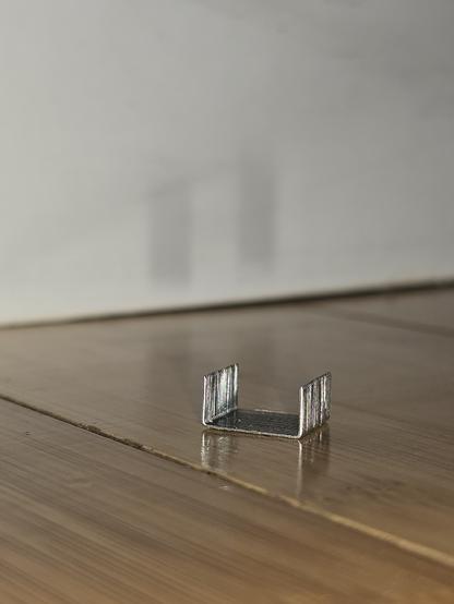 Small sleeve of staples facing points up on the floor, ready to be stepped on by someone's bare foot