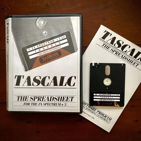 Photograph of the clamshell case, manual and 3" disk for Tasman Software’s “TASCALC” which is a spreadsheet application for ZX Spectrum. The styling is familiar among the Tasword family of software. The disk label for TASCALC is metallic gold/bronze colour.