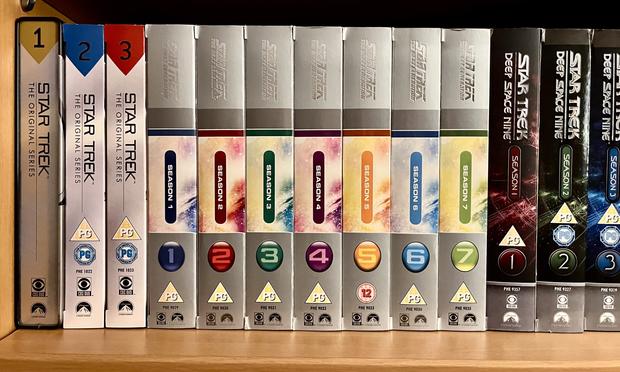 A shelf displaying DVD box sets of "Star Trek," including "The Original Series" and "Star Trek: The Next Generation," along with "Star Trek: Deep Space Nine." The boxes are organized by season, with colorful designs and labels