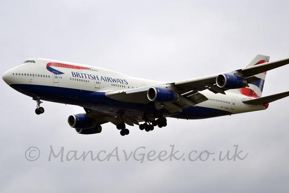 Low side view of a very large, 4 engined jet airliner flying from right to left at a very low altitude, with flaps fully deployed from behind the wings and the undercarriage extended, suggesting it is about to lane.
The plane is mostly white, with a dark blue belly and engine pods, dark blue £British Airways" titles on the forward fuselage, and a curled ribbon on the forward upper deck, red on one side and blue on the other.
There is a red, blue, and red wavy stripe on the tail.
Cloudy grey skies fill the rest of the frame.