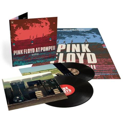 Una caja de un disco de vinilo de Pink Floyd en Pompeya (1972). La portada principal muestra una imagen de estilo retro con tonos rojizos y azulados, figuras caminando sobre un muro y el título del álbum. Incluye una portada interior con una foto de la banda en el escenario con equipo de sonido. La caja también contiene dos discos de vinilo negros. La parte trasera de la caja continúa con la estética de la portada y anuncia el álbum como “más que una película, un concierto explosivo”.