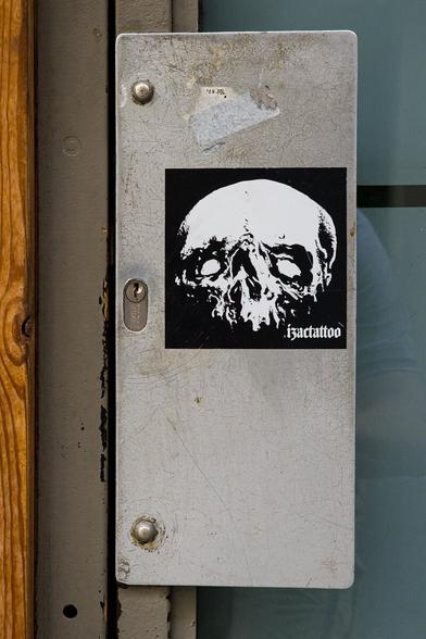 A door handle with a sticker of a skull on it.