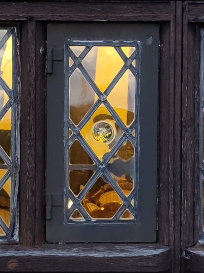 Reproduction leaded glass window in diamond pattern with bullion piece in centre. Approx 55cm high by 25cm wide. Set in old, weathered oak frame.