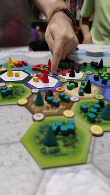 Left hand pointing to the game board of Dominant Species.