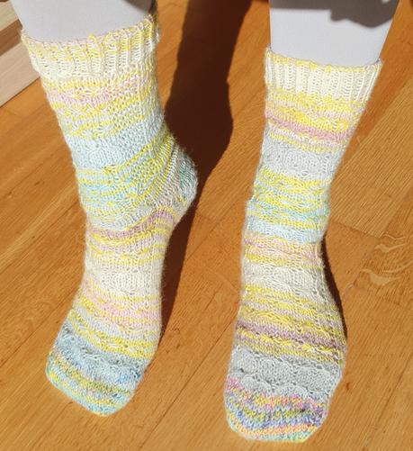 Picture of my legs with socks in self striping yarn in soft light colors, with cables in front
Photo de mes jambes ou je porte des chaussettes en laine autorayante de couleurs claires et douces, avec des torsades sur le devant