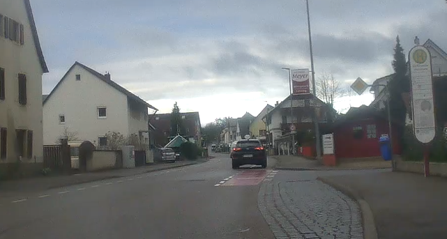 Breite Ortsdruchfahrt mit Radfahrschutzstreifen in beide Richtungen. Kein Gegenverkehr - als vieeeel Platz auf der Fahrbahn. Das Fahrzeug voraus belegt ca. 80% vom Radfahrschutzstreifen.