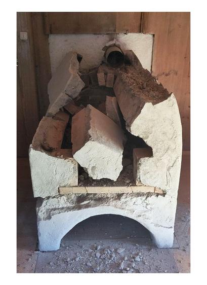 A demolished old oven in pieces of fireclay bricks. Wooden paneling in the background.