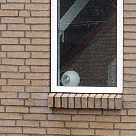 A spherical lamp with a circular metal plate that looks like an eyeball.