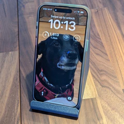 a  photograph of an iPhone 15 Pro max in a case in the stand.