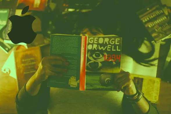 A person reading the book 1984 from George Orwell. In the upper-left corner is the Apple logo but with two bites taken off the apple instead of only one.