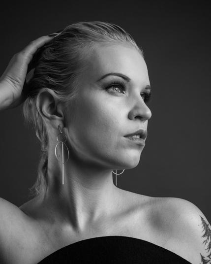 A sophisticated black and white studio portrait of a woman with elegant lighting, soft shadows, and an introspective expression. Professional portrait photography by Kuvaajankulma in Lappeenranta, specializing in artistic and timeless studio sessions