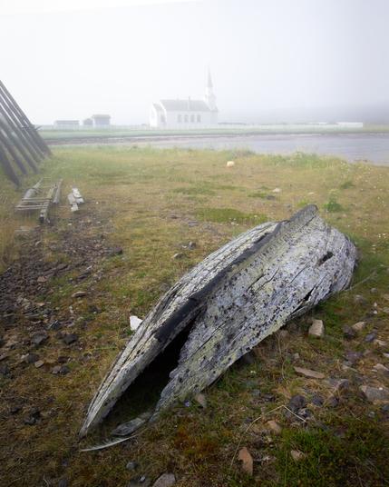 The remains of an old fishing boat, with little white church of Nesseby in the background