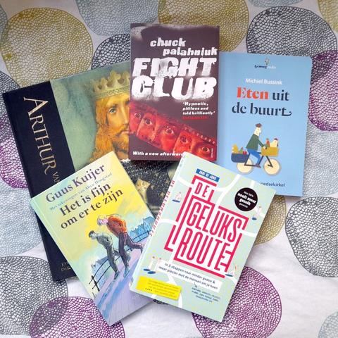 A flat-lay of five books: Arthur of Albion, Fight Club, and three Dutch books whose titles translate to "Local food", "The happiness route" and "It is nice to exist"