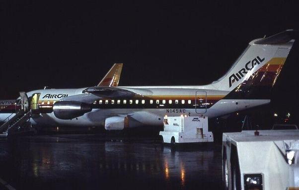Jet is parked at night with the lights on. You can see the air stairs are deployed and there is a warm light emitting out.