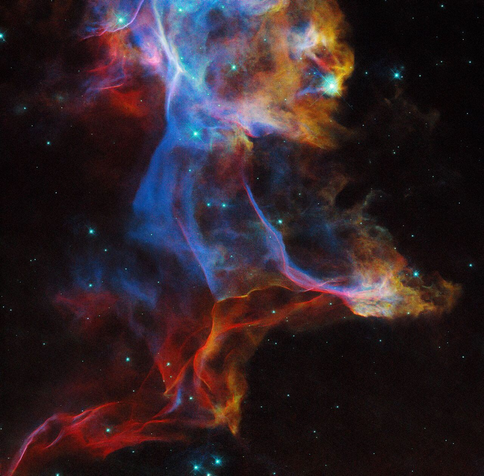 Hubble Space Telescope composite image of the Veil Nebula - a supernova remnant in the constellation Cygnus. 

The photograph shows a wispy structure in an array of colors in the enter of the image. The background is black, but some green spots are scattered across the image.