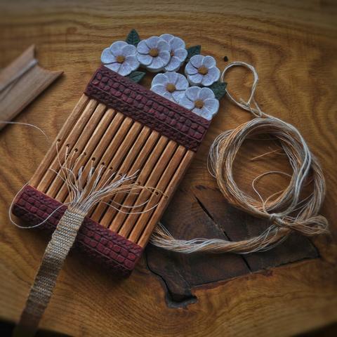 Rigid heddle, with a motif of white flowers.