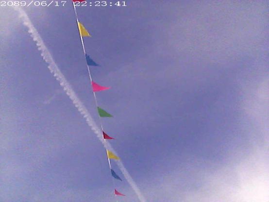 Small colored flags against the sky. A plane trail.