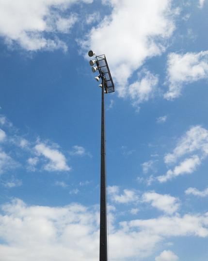 Stadium lights in front of a partly cloudy blue sky