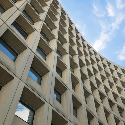 Looking up at a curved brutalist concrete building with lots of small square windows