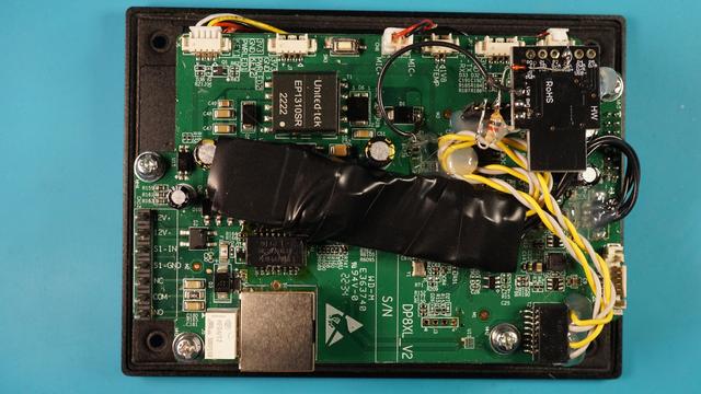 Leiterplatte der Türklingel in Nahaufnahme mit darauf liegenden in Isolierband eingewickelten USB-Netzwerkadapater