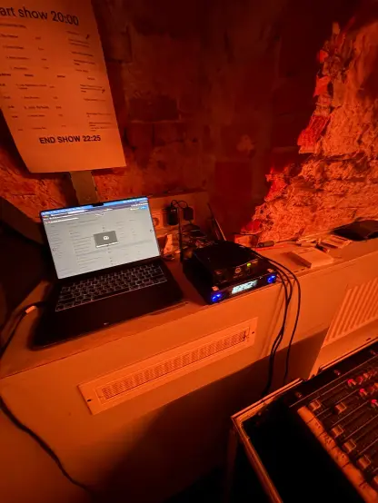 A laptop with on the right 2 wireless receiver and above the laptop the show schedule