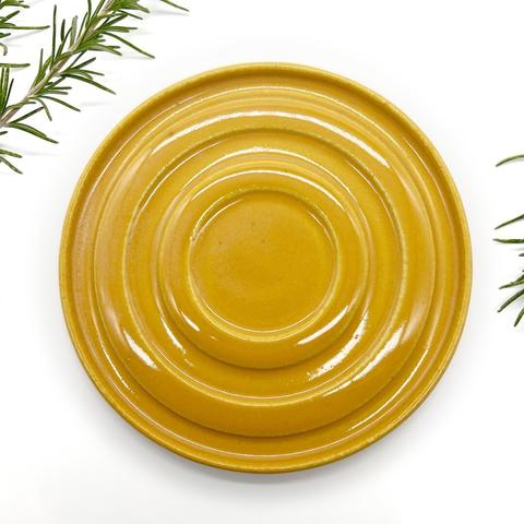 A yellow plate featuring a delicate green sprig placed elegantly on top.