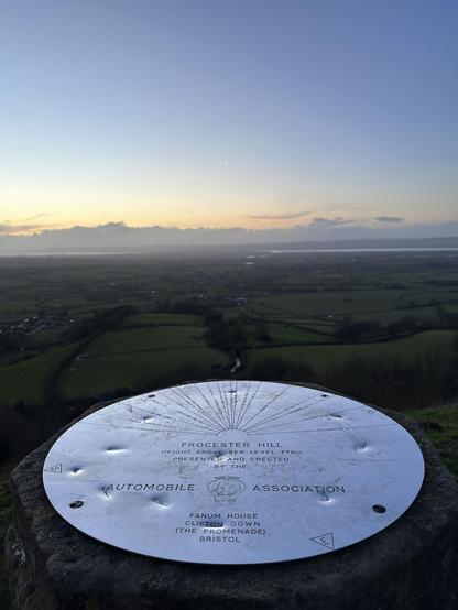 A viewpoint dial with place names lit by the sunset over the Severn Valley in Western England