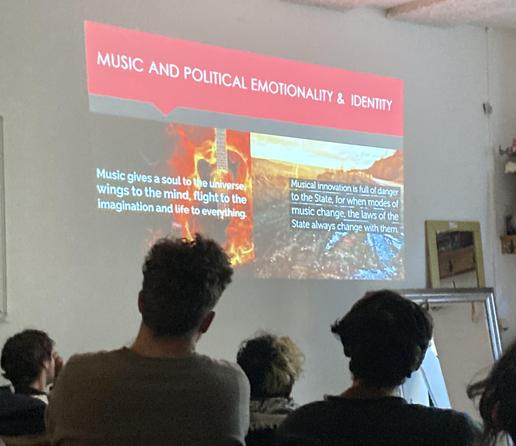 from behind plp watching a screen with presentation.
'music and political exmotionallity & identity'