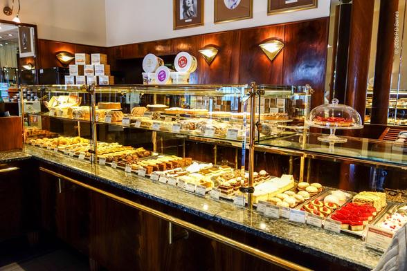 Display cabinet inside Café Blikle showing row upon row of cakes, tarts, doughnuts and other pastries.