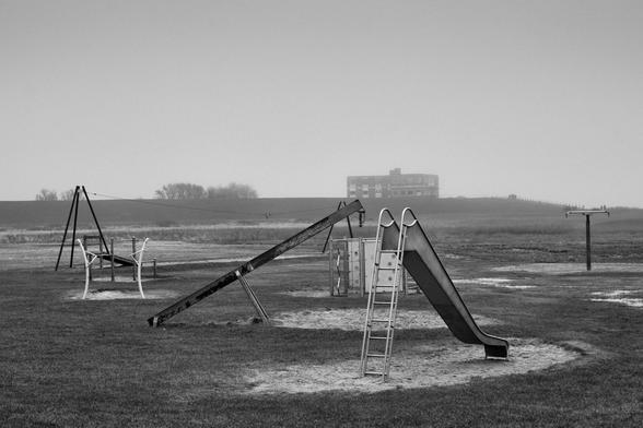 Verlassener Spielplatz am Strand vor Hotel-Ruine, Schwarzweiß Foto; Abbondoned playground a the Beach infornt of burn down hotel, blanck and white photo;