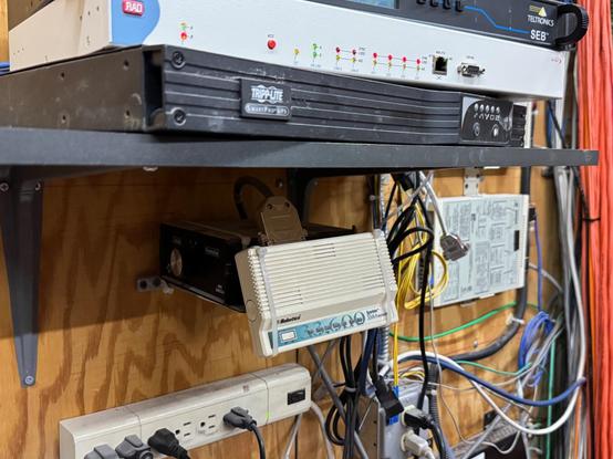 A 33.6Kbps modem hanging from the wall of a network closet by its serial cable, long unused