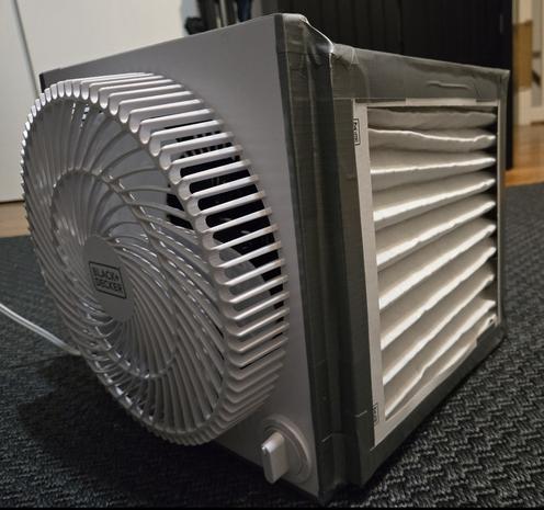 A small white fan with 10-inch air filters duct-taped to it to form an air filtering cube.