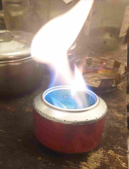 Réchaud en canette aluminium allumé.
Le feu est au milieu, une grande flamme sort.
Pas de feu par les trous.
Casserole et chapeau anti-condensation en arrière-plan