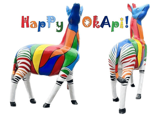 Two colourful statues of an okapi painted in completely unnatural bright colours. The words “Happy Okapi” are written above in wild, colourful letters.
