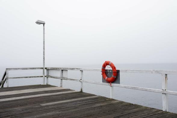 a bridge with a red lifesaver on a foggy day