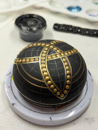 The stone in progress, with the triquetra knot outlined in gold and filled with gold dots.