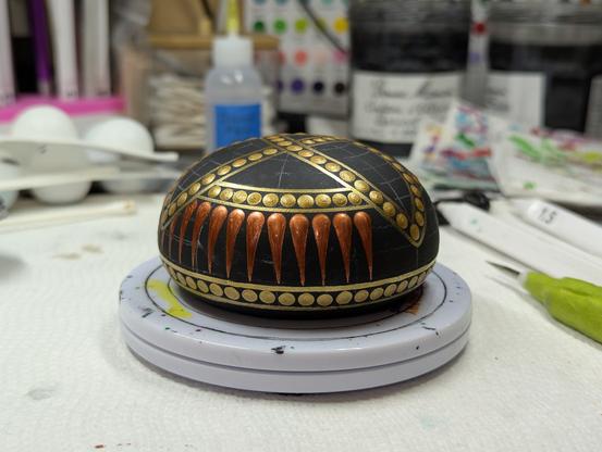 The copper swooshes of the side band have been started; they're shiny and still wet.