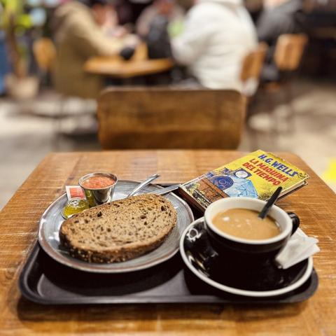 Bodegón estándar de desayuno con tostada de tomate y aceite en pan de cereales, café rico, pero rico, con leche fría de avena y la edición ilustrada de Bruguera de La Máquina Del Tiempo.