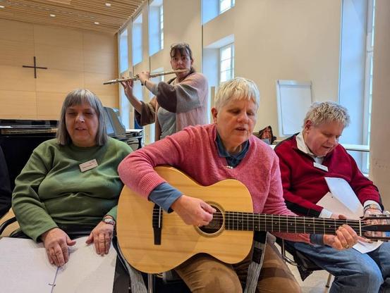 V.r.n.l. Heike Kühner mit Liedblatt in Punktschrift, Dagmar Holtmann mit Gitarre und Udo Holtmann ebenfalls mit Punktschriftliedblatt. Die Flöte spielt Ulrike Erlewein (dahinter in der Mitte)