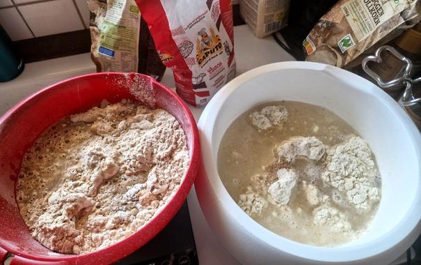 2 Schüsseln mit Wasser und Mehl. Links rote Schüssel mit Brotteig rechts weisse Schüssel mit Pizzateig.