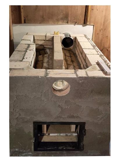 Oven ceiling opened with view of the two heating elements of the oven. Old oven door frame refitted in front of the ofen entrance. A old wooden paneling is visible on the left, top and right edges of the photo.