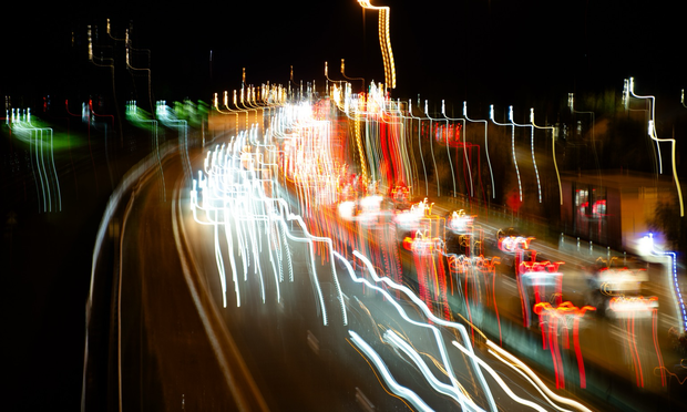 Looking down at the light trails of car lights on a busy highway at night. The camera has been moved to make the trails vertical as well as horizontal.