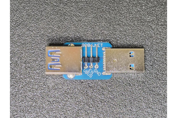 Small blue PCB with a USB 3 Type-A plug and socket on each end with a 3-pin header in between labelled VBUS/EN/GND.