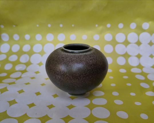 A miniature round bowl-shaped ceramic with a matt brown and green glaze.