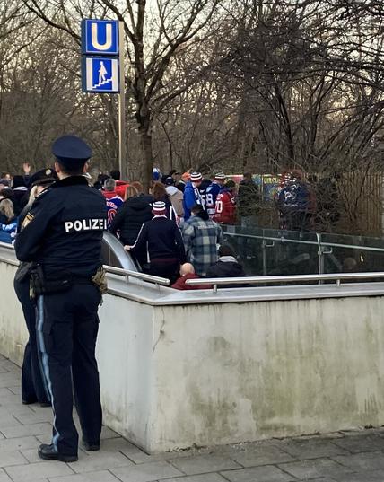 Foto eines u Bahn Ausganges, davor steht Polizei im Hintergrund uriniert eine Gruppe an einen Zaun