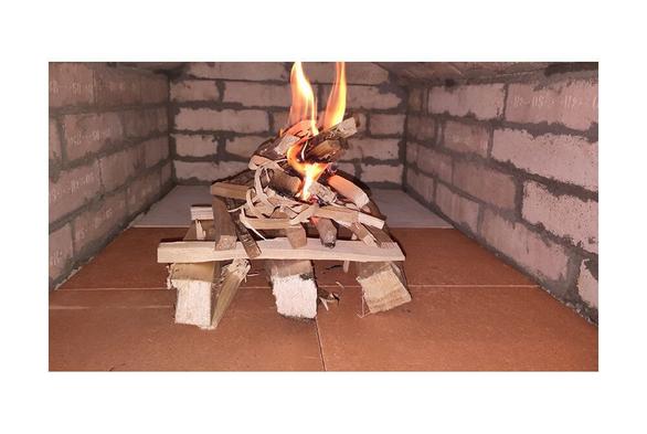First small fire in a new oven interior with flat vault. Smoke outlet at the back left of the combustion chamber. Wall and arch made out of fireclay bricks. Bottom of the oven lined with special fireclay baking plates.